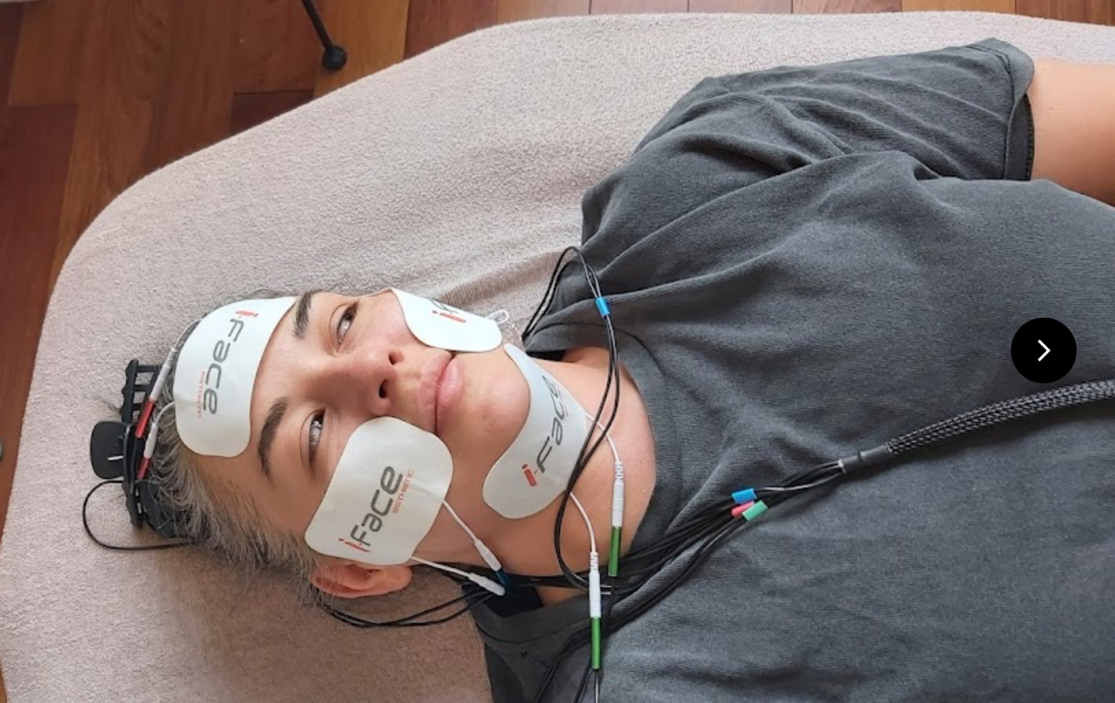 Klient modtager EMS ansigtsbehandling med iFace elektroder på pande, kinder og hals hos Klinikken Harrison